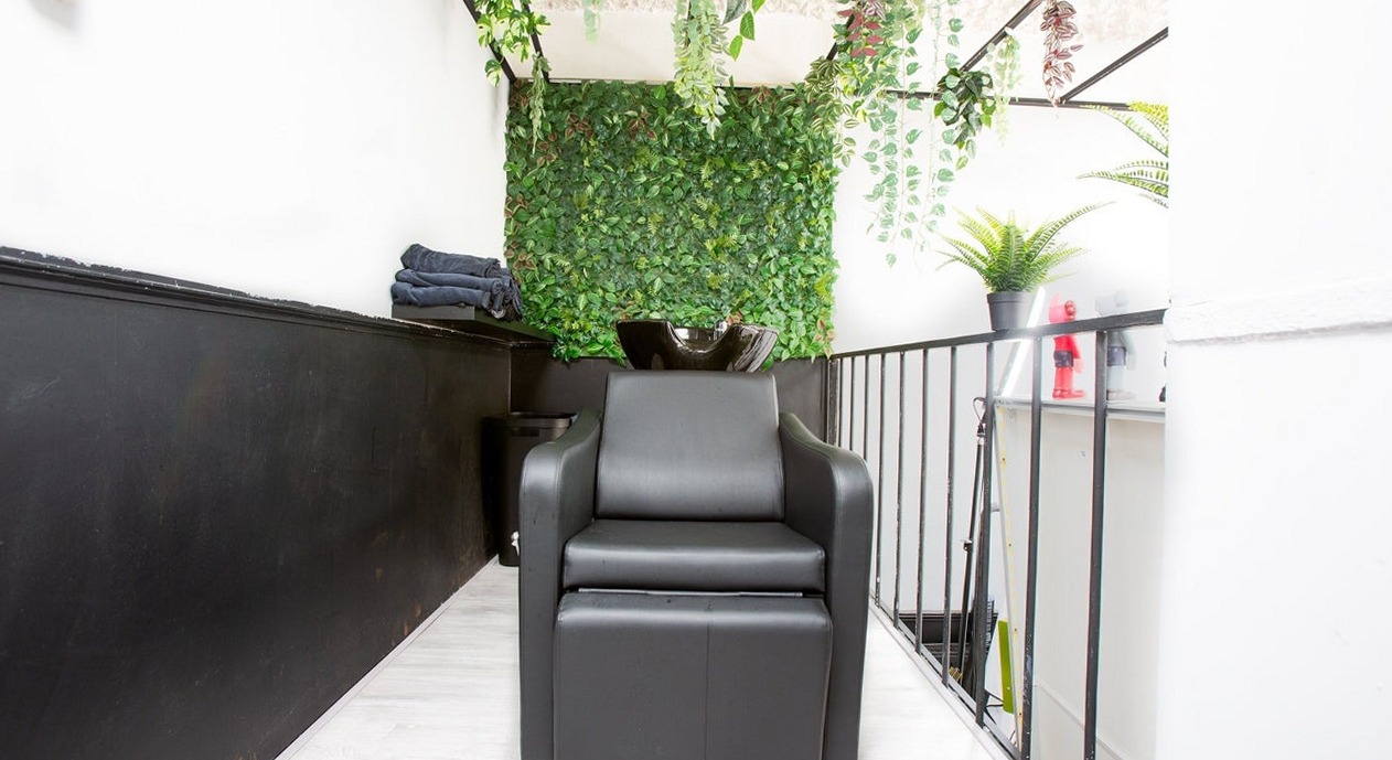 De wasplek met een zwarte wasstoel voor een groene plantenwand