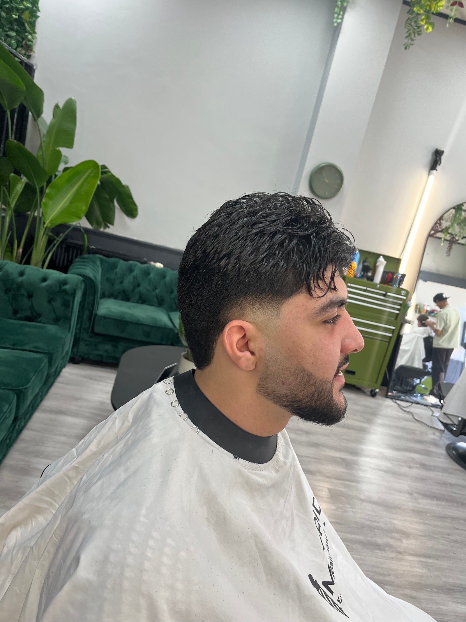 Fade met baard, van opzij, met de groene bank op de achtergrond